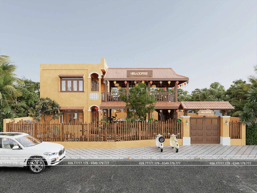 View của quán từ ngoài cổng nhìn vào, xung quanh là cây cối và quán nổi bật hơn với màu vàng của Hội An