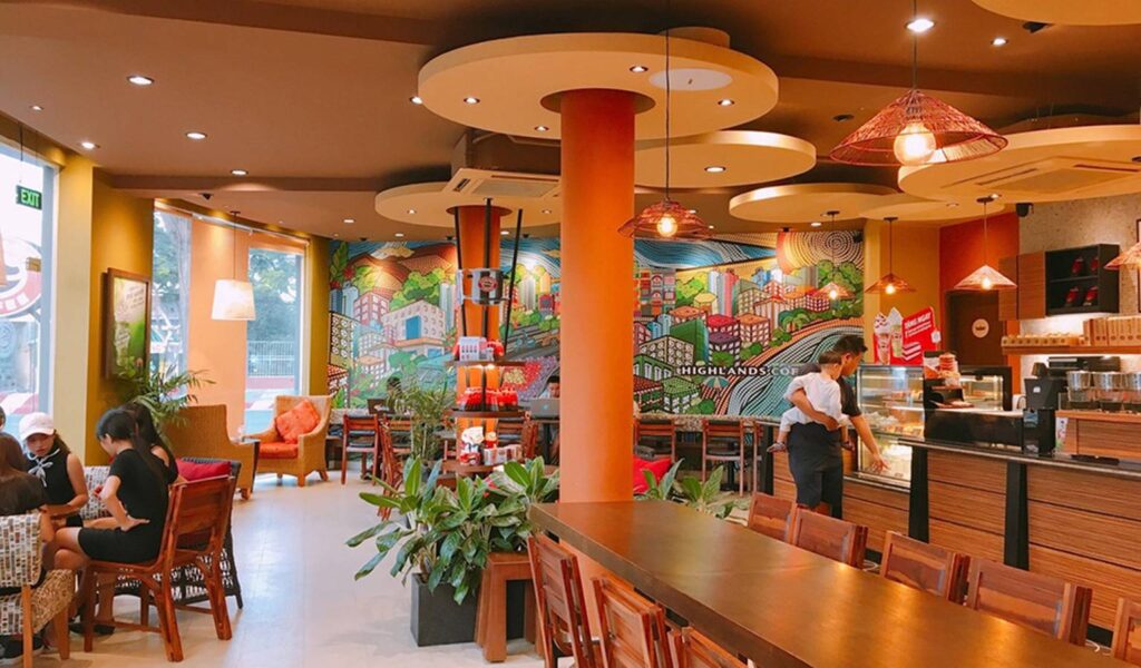 Thiết Kế Quán Cafe Highlands Bản Sắc Việt Trong Không Gian Hiện Đại 3 Không gian quán Highlands với tông nâu đỏ đặc trưng, nội thất gỗ và tường gạch mang phong cách bản địa.